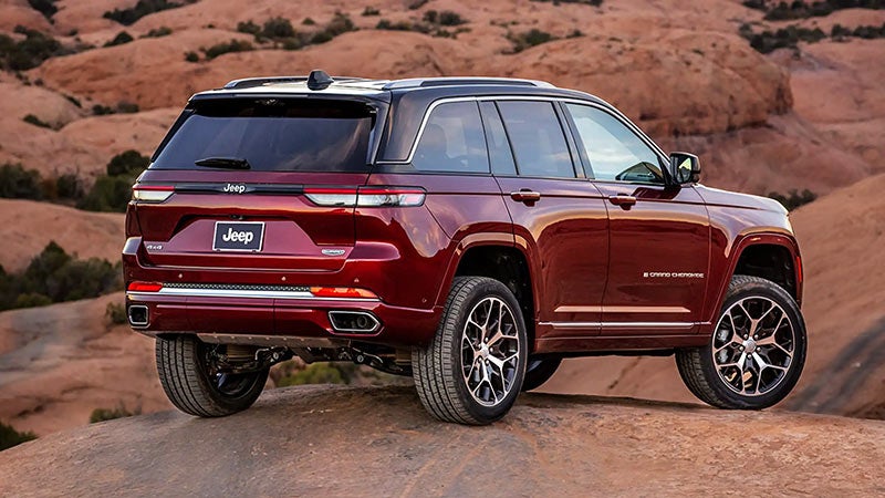 Red Jeep Grand Cherokee parked on red rock, seen from the rear.