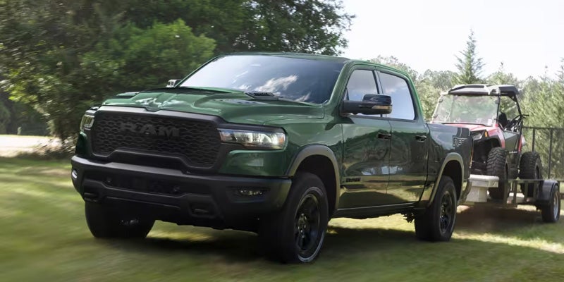 Front view of a green pickup truck pulling a trailer outdoors