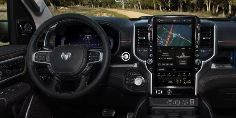 Car interior with a Ram steering wheel and a large vertical touchscreen displaying a navigation map.