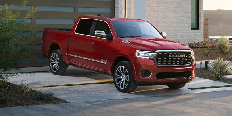 Red pickup truck parked in driveway outside modern residential house.