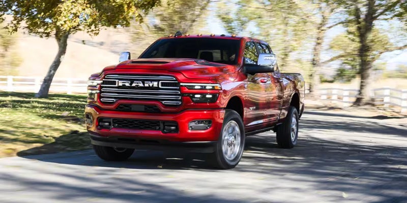 Red Ram 2500 pickup driving on a tree-lined road.