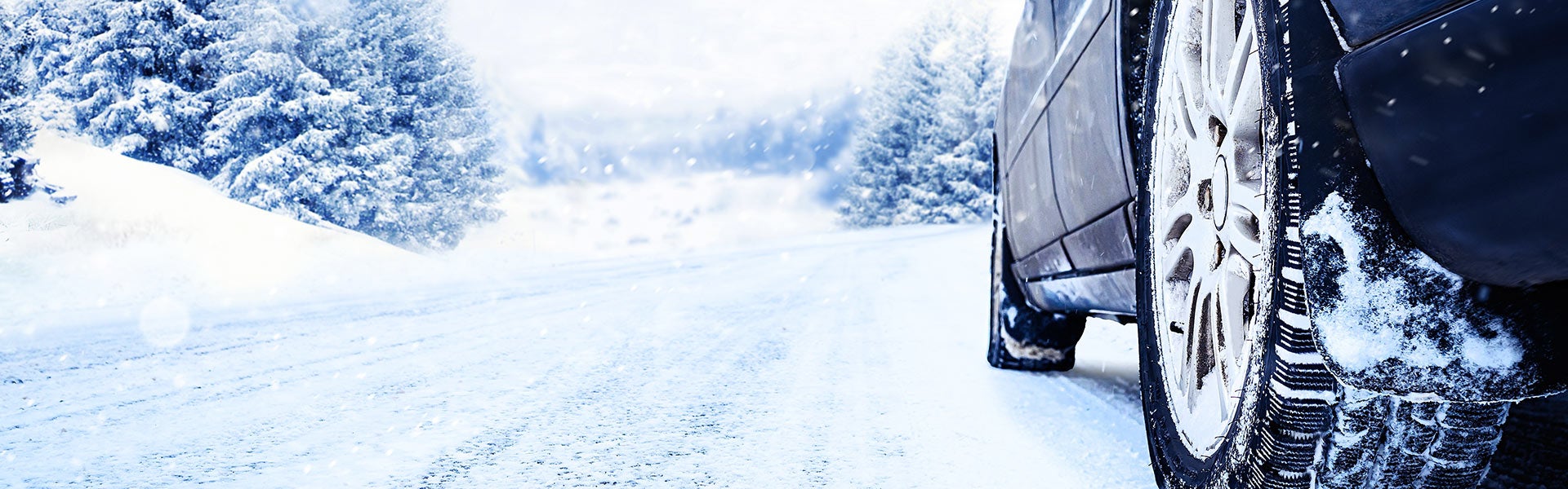 Close-up of a vehicle tire driving on a snow-covered road in winter conditions.