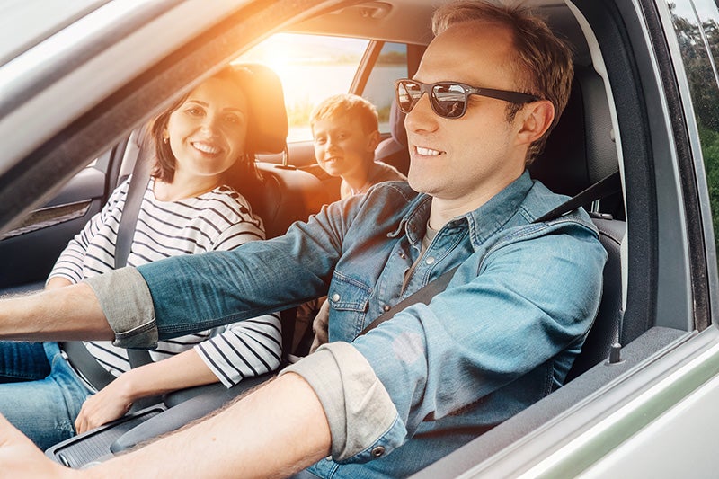 Happy family (father, mother, and child) on a sunny car trip.