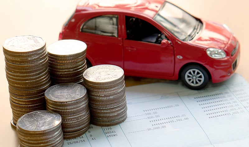 Car financing concept with coin stacks, financial paperwork, and a red model vehicle